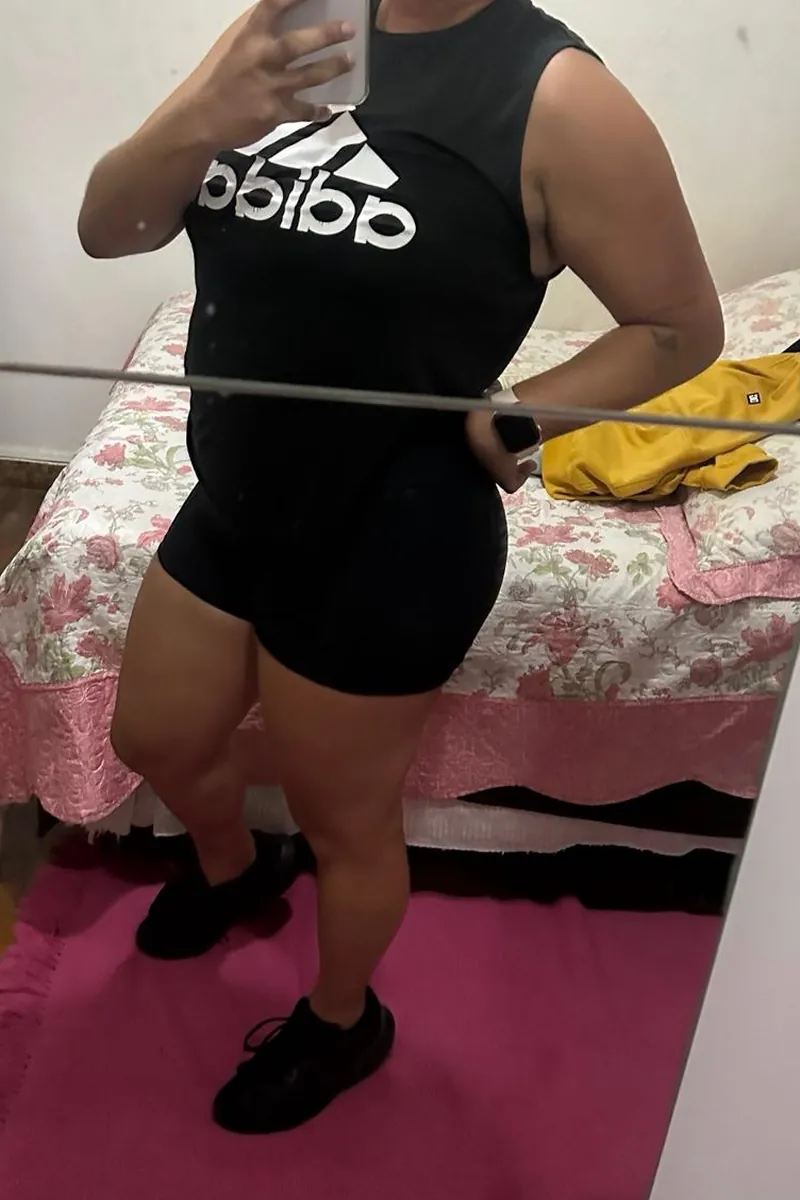Aluna antes do acompanhamento, de regata preta e short, em foto no espelho do quarto